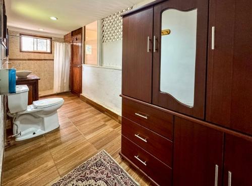 a bathroom with a toilet and a large wooden cabinet at Mckay's Quinta in Yaruqui