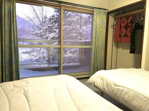 a bedroom with a view of a snow covered window at コンドミニアム定山渓307 in Jozankei