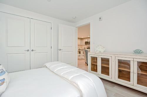 a white bedroom with a bed and a kitchen at Harbourtown Suites, Unit 213 in Plymouth