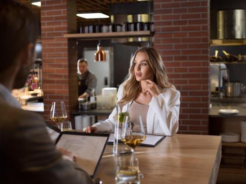 a woman sitting at a table in a restaurant at City Park Hotel & Residence in Poznań