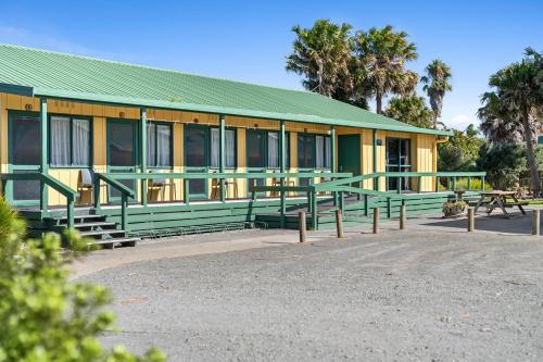 a green and yellow building with benches in front of it at Tasman Holiday Parks - Miranda in Miranda