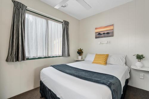- une chambre avec un grand lit et une fenêtre dans l'établissement Tasman Holiday Parks - Miranda, à Miranda