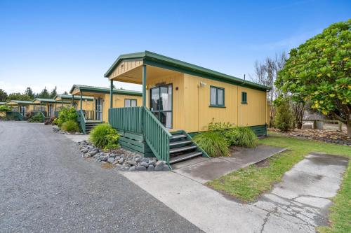 a yellow house with a green porch on a street at Tasman Holiday Parks - Miranda in Miranda