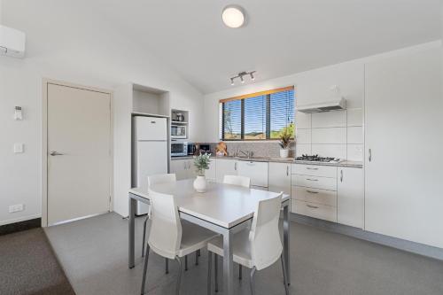 a white kitchen with a white table and white chairs at Tasman Holiday Parks - Miranda in Miranda