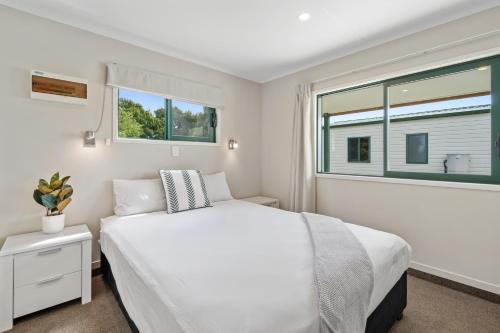 a white bedroom with a bed and a window at Tasman Holiday Parks - Miranda in Miranda