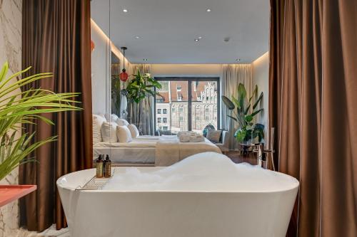 a bathroom with a bath tub and a bedroom at Deo Plaza Riverside & Radisson SPA by Downtown Apartments in Gdańsk