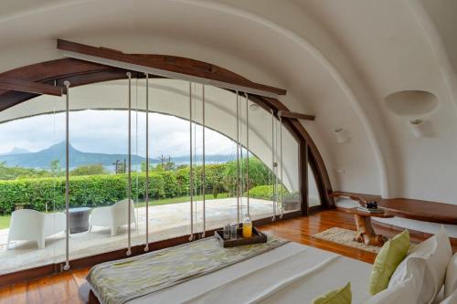 ein gewölbtes Zimmer mit einem großen Fenster und einem Sofa in der Unterkunft Resort Amanzi in Lonavla