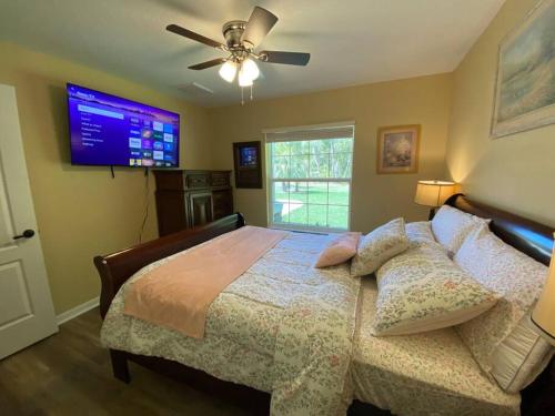 a bedroom with a bed with a ceiling fan and a television at Sundance' Acres *Brand New House*with hot tub in Spring Hill