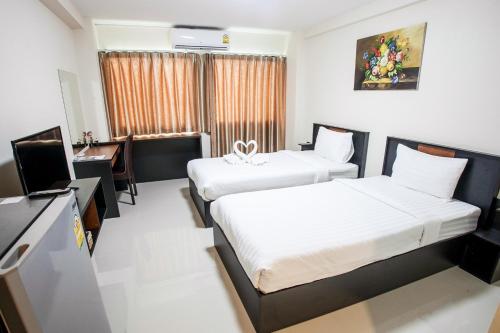 a hotel room with two beds and a desk at Tone Condorent Hotel in Chachoengsao