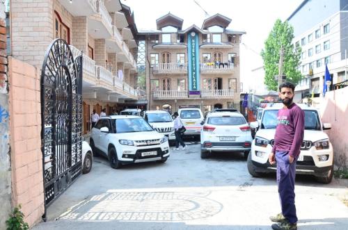 a man standing on a street with cars parked at hotel city plaza in Srinagar