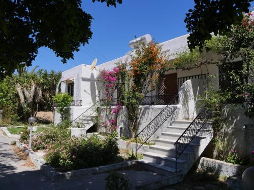 Una casa blanca con escaleras y flores. en Helios Rhodos Apartments 1 en Koskinou