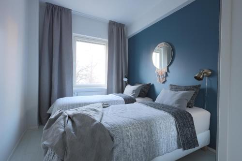 a blue bedroom with two beds and a mirror at Urban Oasis - Two Bedrooms - Balcony - Nearby Metro in Helsinki