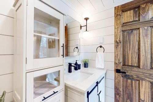 a bathroom with a sink and a wooden door at Bald Mountain Tiny House in Bucksport