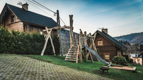 a playground with a slide and a wooden house at Jaworowa Osada in Brenna