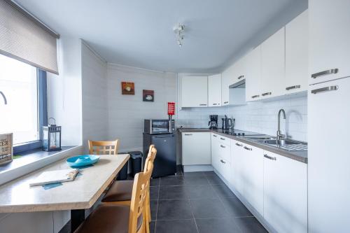 a kitchen with white cabinets and a table and chairs at Appartementen The Place 2 Beer in Bullange