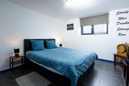 a bedroom with a bed with a blue comforter at Appartementen The Place 2 Beer in Bullange