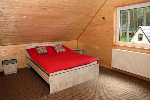 a bedroom with a red bed in a wooden cabin at Blue Resort Ostrowo in Ostrowo