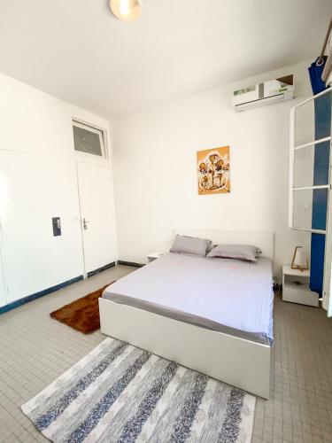 um quarto branco com uma cama e um tapete em Ideal F3 em Dakar