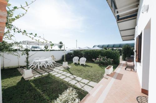 a patio with white tables and chairs in a yard at Gioema in Borgo Vodice