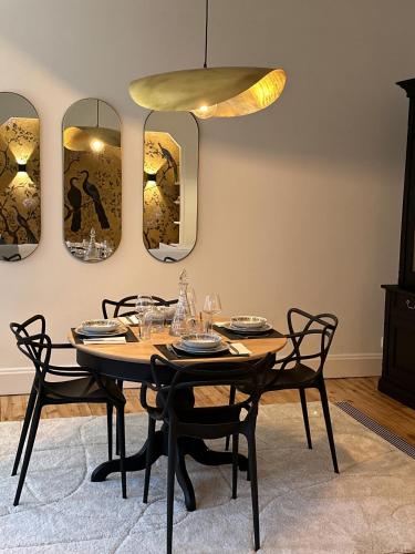 - une salle à manger avec une table, des chaises et des miroirs dans l'établissement Appartement Eugénie, à Vichy