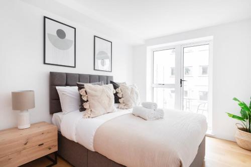 a white bedroom with a large bed with pillows at Fitzrovia with Balcony - CityApartmentStay in London