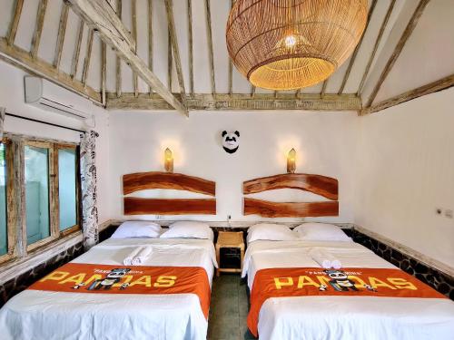 a room with three beds and a panda sign on the wall at Panda Home in Gili Trawangan