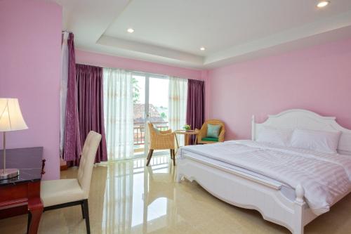 a bedroom with a white bed and a desk and a window at Takanta Place in Udon Thani