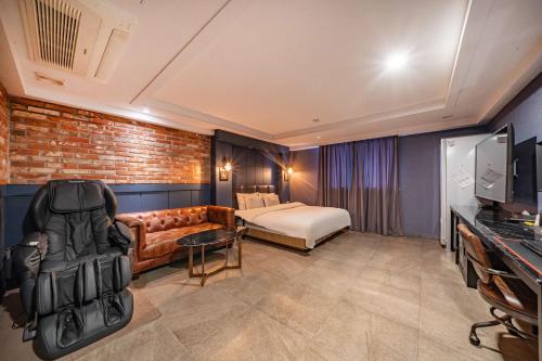 une chambre d'hôtel avec un canapé et un lit dans l'établissement 호텔 소설스미스( Hotel Soseol Smith), à Cheonan