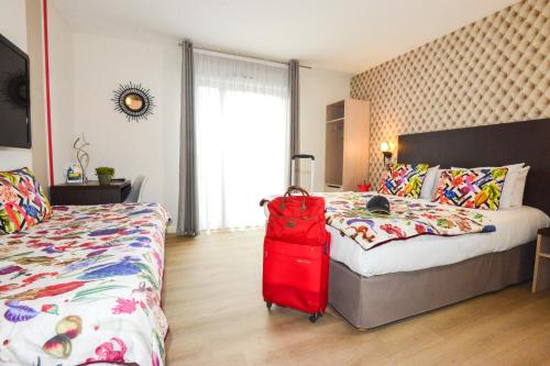 a bedroom with a red suitcase next to a bed at Hôtel Villa Sophia - ADULTS ONLY JULY AND AUGUST in Mougins