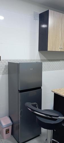 a kitchen with a stainless steel refrigerator and a stool at WestMore Court a.k.a The Family House in Ibadan