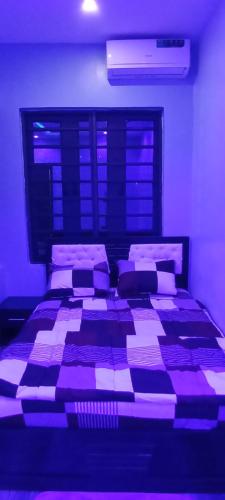 a bedroom with a large bed with purple lighting at WestMore Court a.k.a The Family House in Ibadan