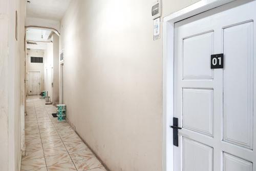 un corridoio vuoto con porta bianca e pavimento piastrellato di RedDoorz Syariah near Transmart Jambi a Palmerah