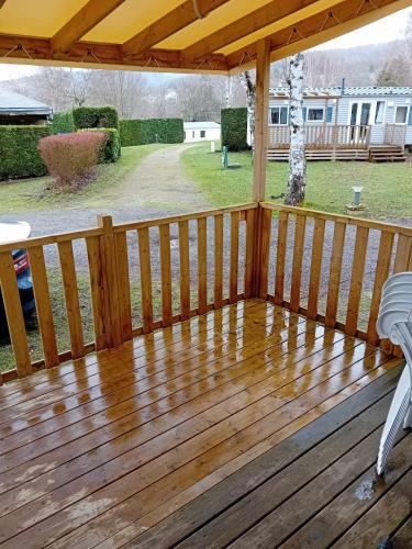 a wooden deck with a table and a chair on it at mobilhome 5 couchages in Nages