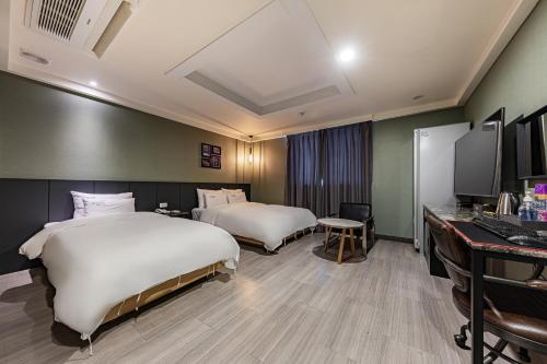 a hotel room with two beds and a desk at Hotel Soseol Smith in Cheonan