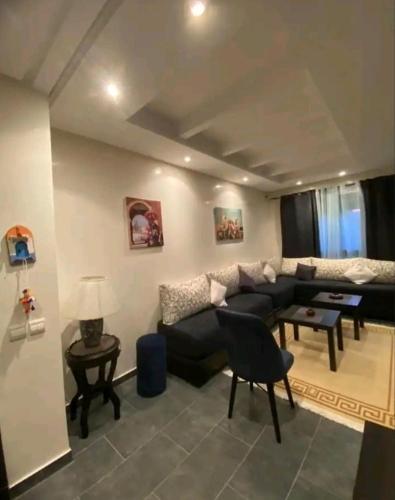 a living room with a black couch and a table at Pied sur mer "Un paradis à bas prix" in Tamaris