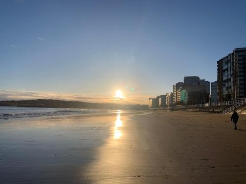 een persoon die bij zonsondergang op het strand loopt bij MenVal16 in Gijón