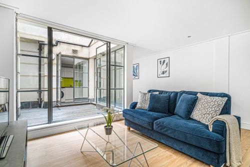a blue couch in a living room with a large window at Heart of Holborn with Patio - CityApartmentStay in London