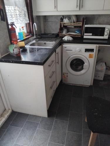 a kitchen with a sink and a washing machine at Furnished Room in a house near train station,bus stop and town center in Plumstead