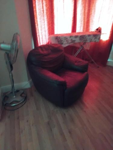 a living room with a red chair and a table at ROOMS IN A HOUSE in Plumstead