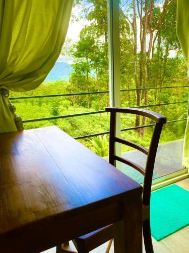 una mesa de madera y una silla frente a una ventana en Mist of Sinharaja Eco Lodge en Galle