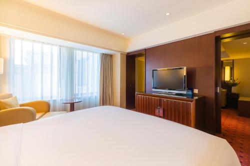 a hotel room with a bed and a flat screen tv at Beijing Pudi Hotel in Beijing