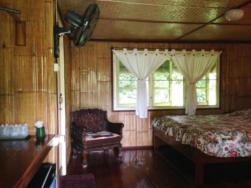 ein Schlafzimmer mit einem Bett und einem Stuhl und einem Fenster in der Unterkunft Yang Tone Farm Stay in Chiang Dao