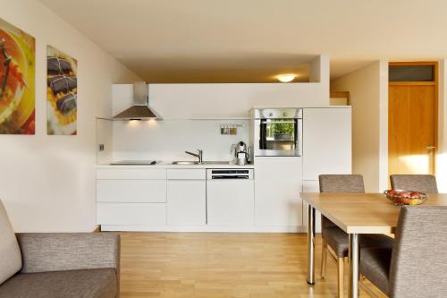 a kitchen with white cabinets and a wooden table at Ferienwohnung iq-Sports in Bludenz