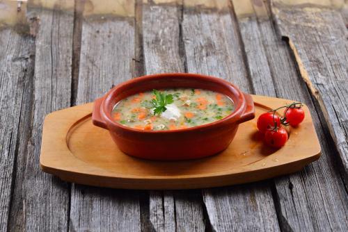 a bowl of soup with tomatoes on a wooden table at Hotel Pahuljica in Vlasic