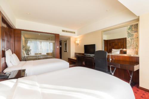 a hotel room with two beds and a desk and a television at Beijing Pudi Hotel in Beijing