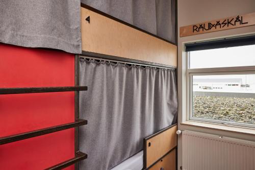 a room with a red wall and a window at Midgard Base Camp in Hvolsvöllur