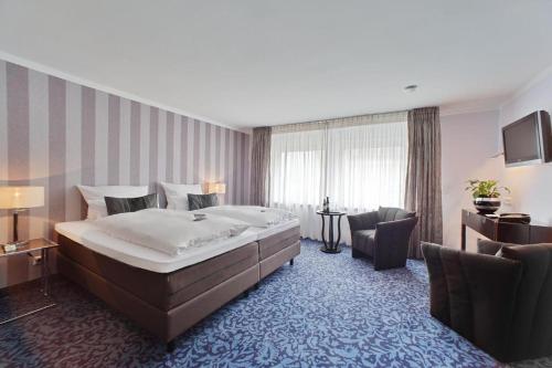 a hotel room with a large bed and a chair at Top Hotel Krämer in Koblenz