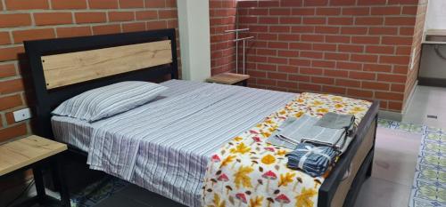 a bedroom with a bed and a brick wall at Apartaestudio 301 velódromo in Medellín