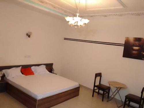 1 dormitorio con 1 cama, 2 sillas y lámpara de araña en HOUSE SOS, en Abomey-Calavi