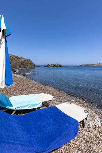アゾリムノスにあるAegean View - Seaside Apartment in Syrosのビーチでのラウンジチェア2脚とパラソル1本